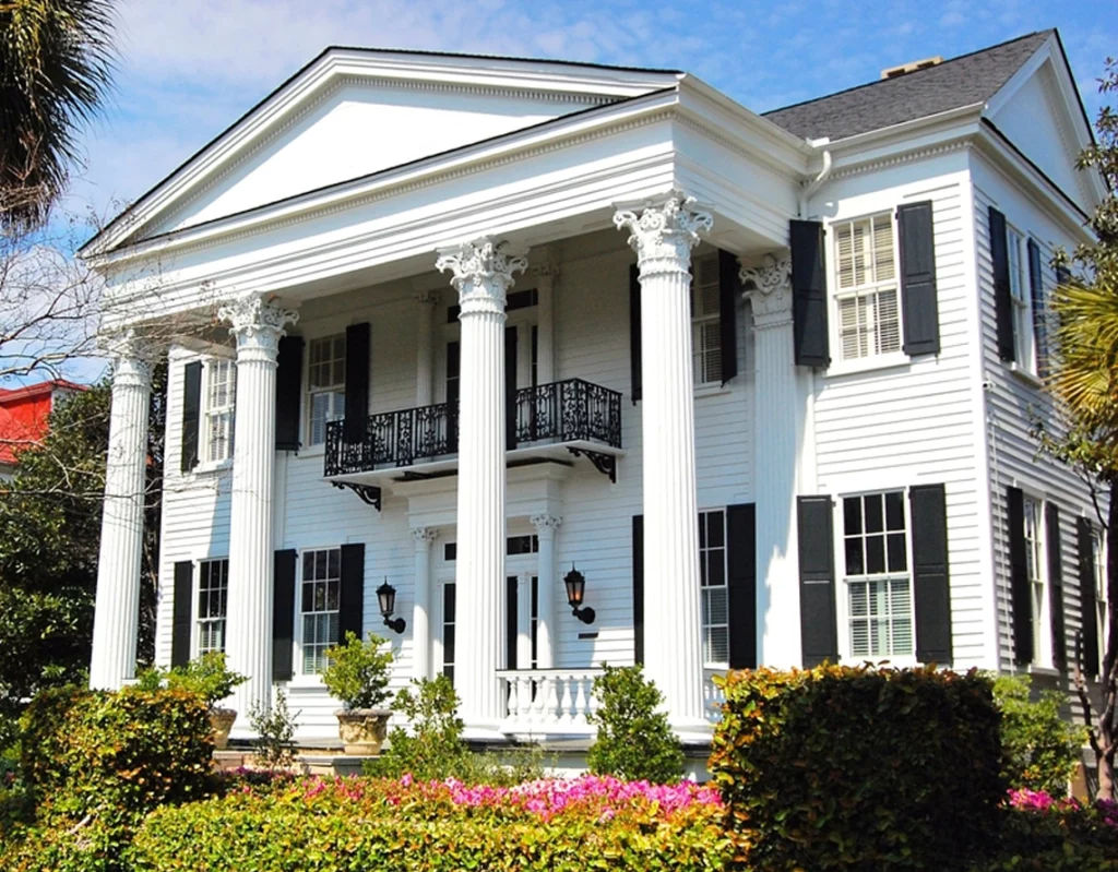Image of a big, high, white house with classic columns, black windows, and lawn.