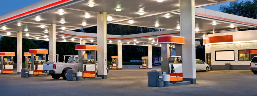 Image of a gasoline refilling station with cars, pickup truck, and convenience store.